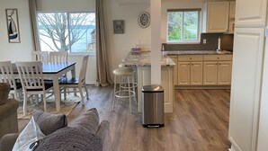 Una cocina moderna con armarios blancos, encimera de granito y refrigerador de acero inoxidable.