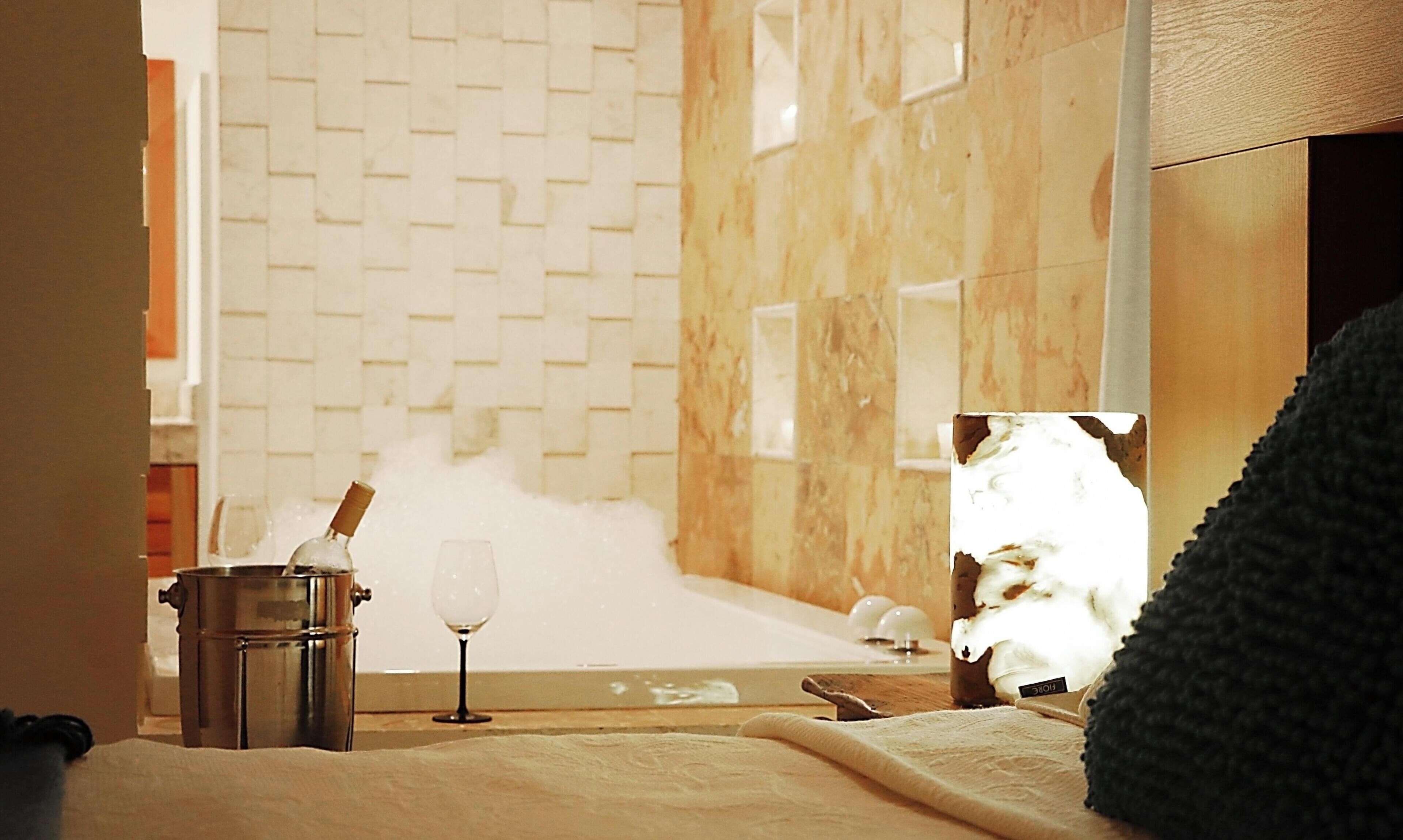 Un espace spa comprenant une baignoire, une bouteille de champagne et un verre.
