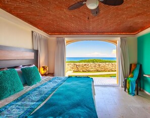 A hotel room with a bed, a view of the sea, a brick ceiling, and a green wall. - Isla 33 Stunning Oceanfront Villa Bienvenida (La Gloria, Isla Mujeres)