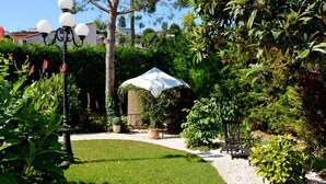 Un jardin bien entretenu, avec une pelouse, des plantes en pot et une pergola recouverte d’un tissu blanc.