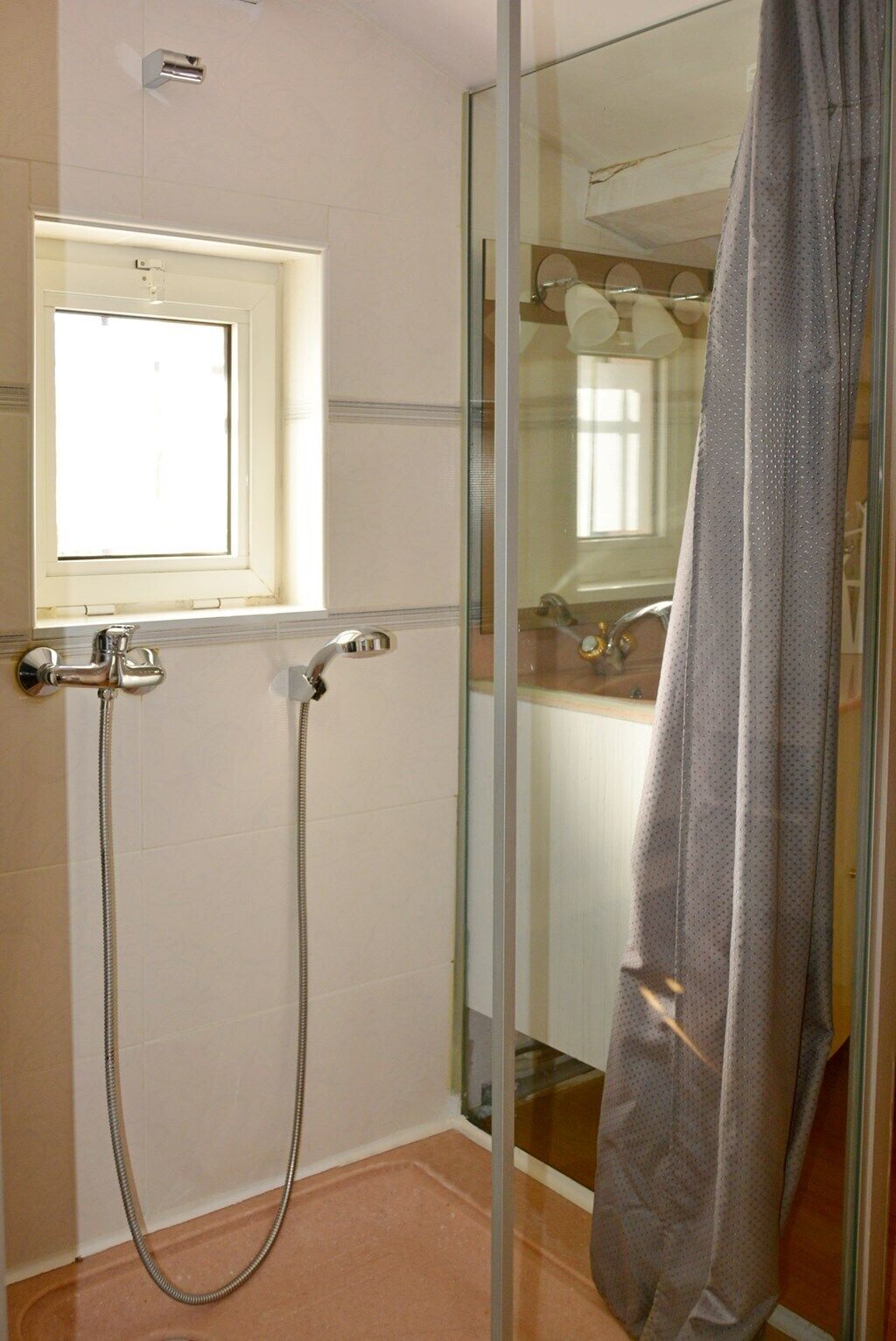 Une salle de bain avec une douche à parois de verre, une fenêtre et une serviette accrochée à la porte.