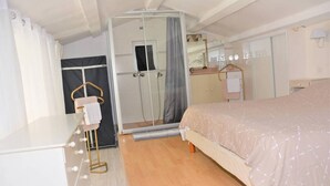 Une chambre à coucher comprenant un lit, un miroir, une armoire et un espace douche.