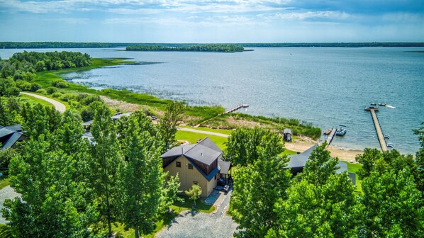 An aerial view of a lakeside property with a house, dock, and boats.
