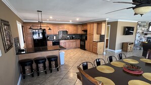 A spacious kitchen with wooden cabinets, a central island, and a dining area with a table set for six.