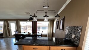 A kitchen with a large island, wooden cabinets, and a black countertop.