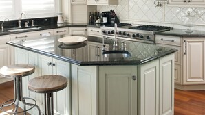 A kitchen with a large island, white cabinetry, and a hanging light fixture. - Luxury Coastal Oasis ~ Panoramic Water Views ~ Wrightsville Beach (Wrightsville Beach)