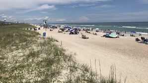 A beach with people, umbrellas, and a lifeguard tower. - Luxury Coastal Oasis ~ Panoramic Water Views ~ Wrightsville Beach (Wrightsville Beach)
