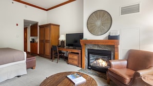 A room with a fireplace, a desk with a computer, a bed, and a leather armchair. - 1117 | Studio | The Mansfield | 1st floor | Private Wooded Mountain Views (Stowe)