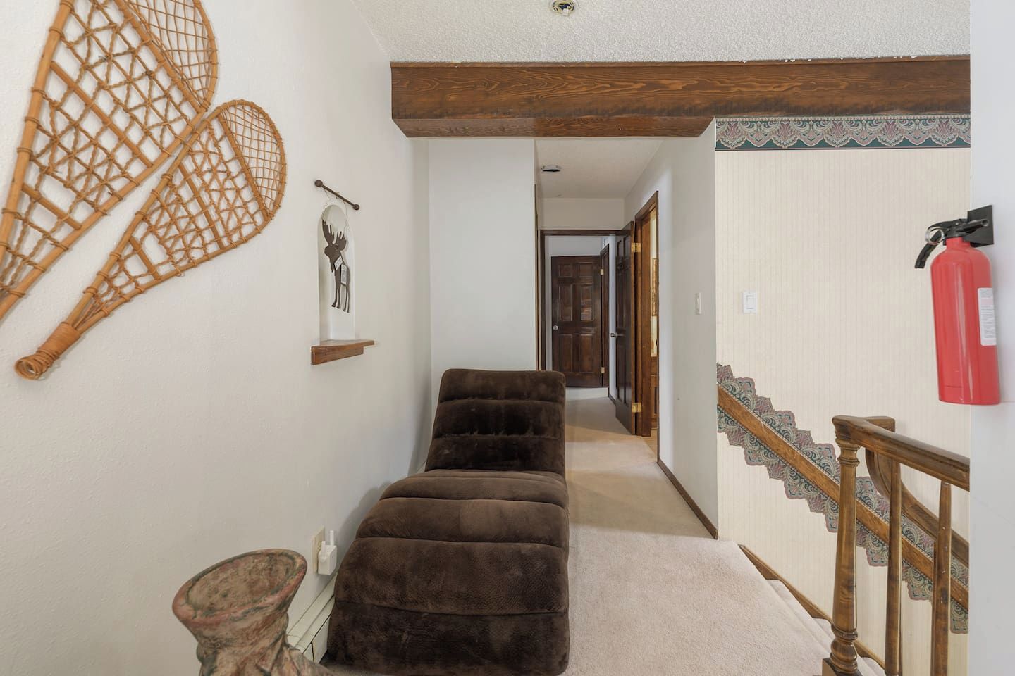 A hallway with a brown sofa, a wooden bench, and a wall-mounted fire extinguisher.