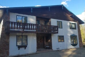 Un edificio de dos pisos con balcón, fachada de piedra y varias ventanas.