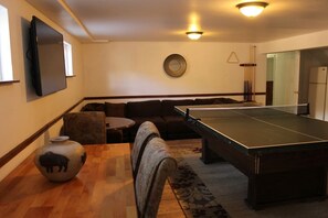 A room with a pool table, a sofa, a small round table, and a decorative vase.