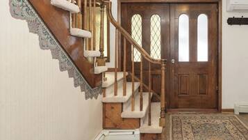 A wooden staircase with a handrail, a patterned carpet, and a door with glass panels.