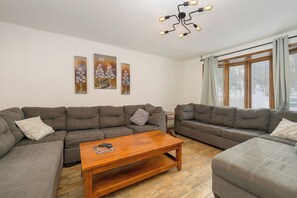 A living room with two grey sofas, a wooden coffee table, and a ceiling light fixture.