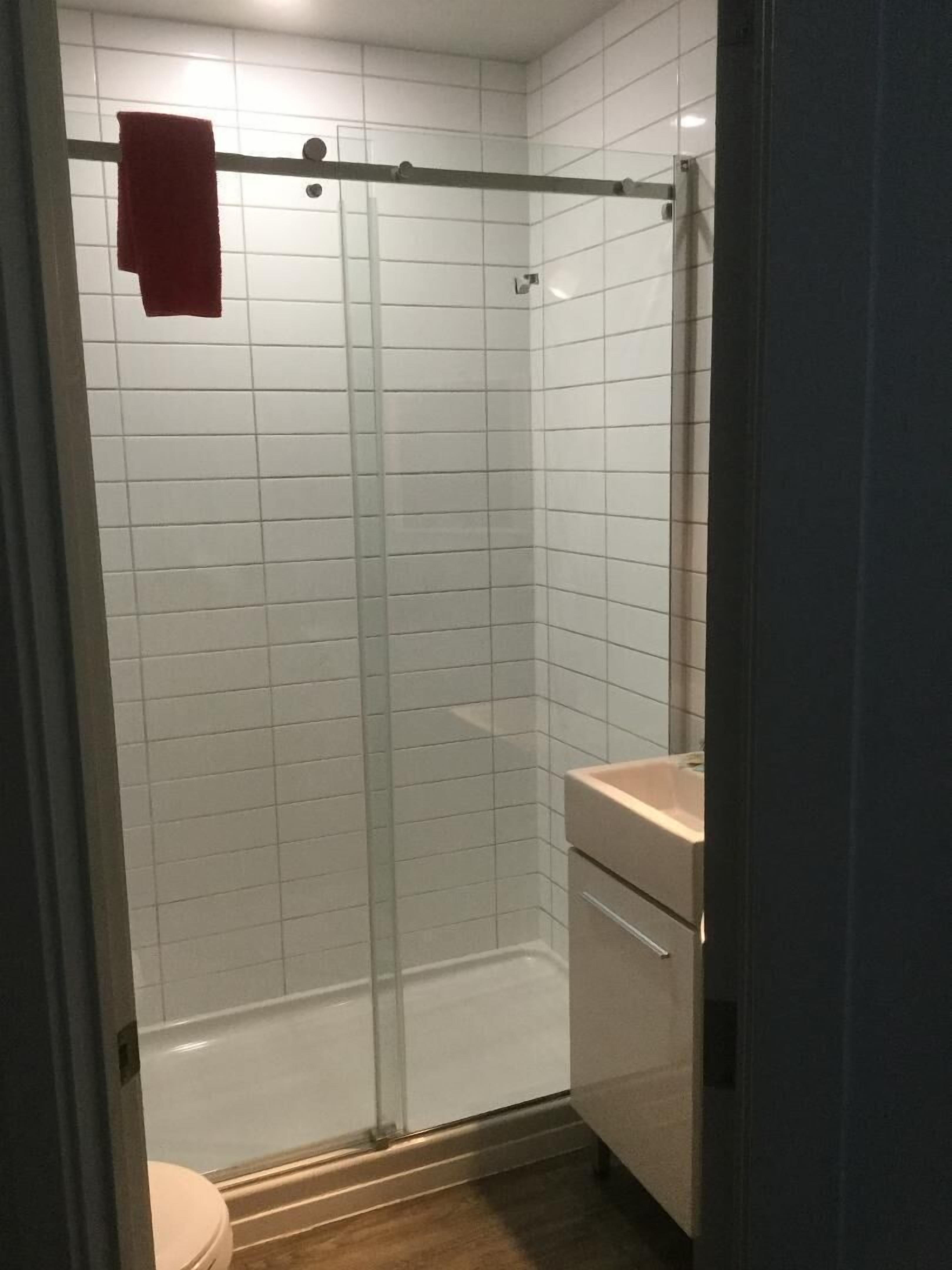 A bathroom with a glass-enclosed shower, a toilet, and a sink.