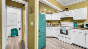 A kitchen with white cabinets, a turquoise refrigerator, and a wooden floor. - Charming Cabana Beach Club #8 - Your Coastal retreat Awaits!#9 also available. (Longboat Key)