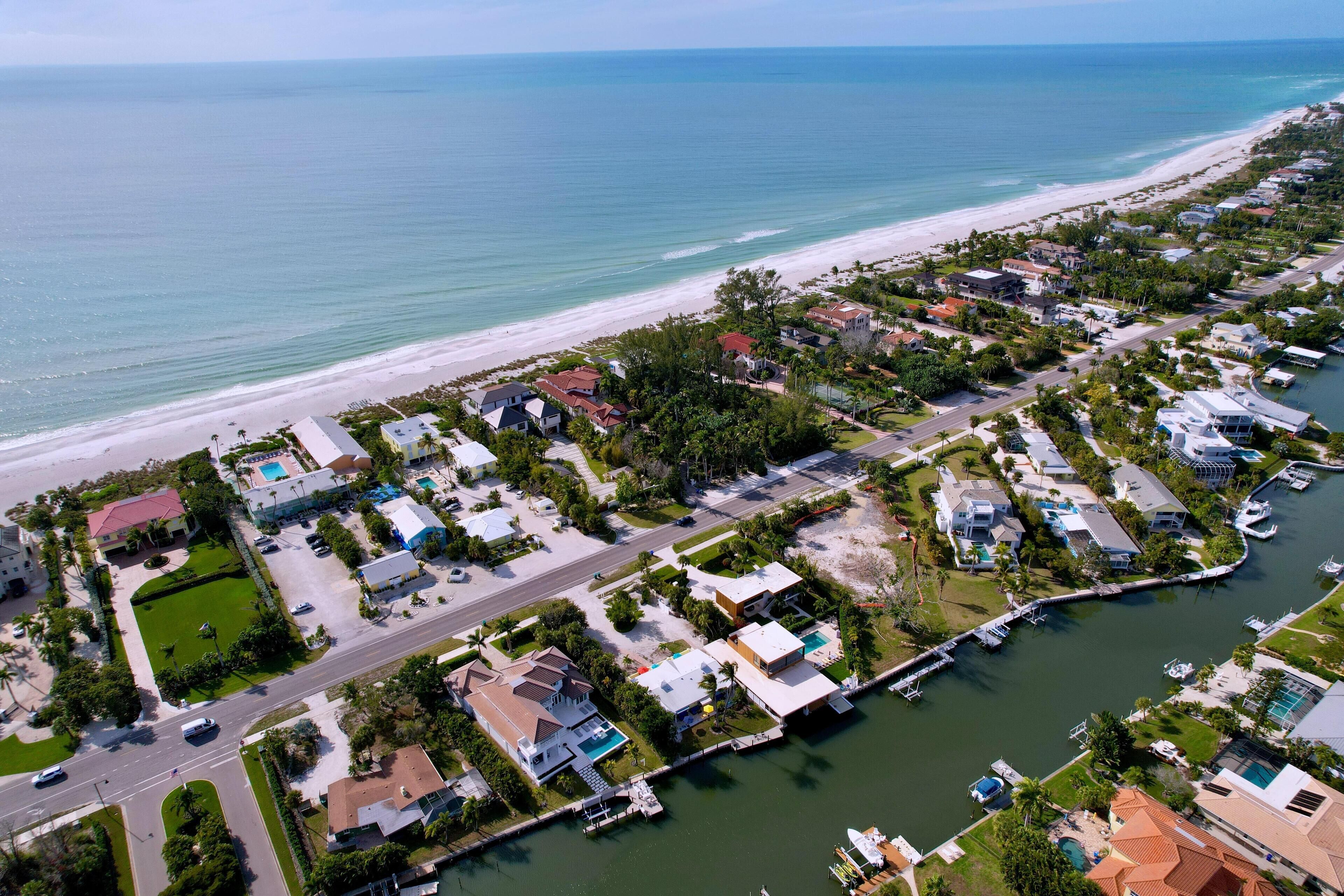 An aerial view of a coastal residential area with houses, a marina, and a beach.