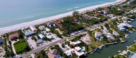 An aerial view of a coastal residential area with houses, a marina, and a beach.
