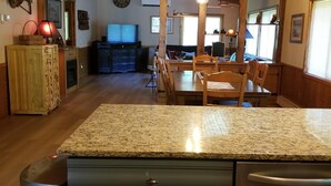 A spacious kitchen with granite countertops, wooden cabinets, and a stainless steel refrigerator. - Kettle River Cabin nestled between the Twin Cities & Duluth, MN (Hinckley)
