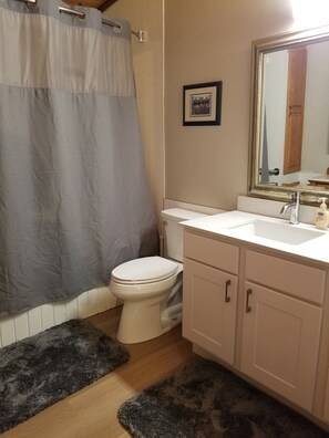 A bathroom with a toilet, sink, mirror, and shower curtain.