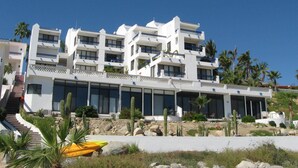 A multi-story hotel with balconies, a pool area, and cacti in the foreground. - Beachfront Condo, Summer Special, 154 u.s.  per night!!!!!!! (Beauna Vista)