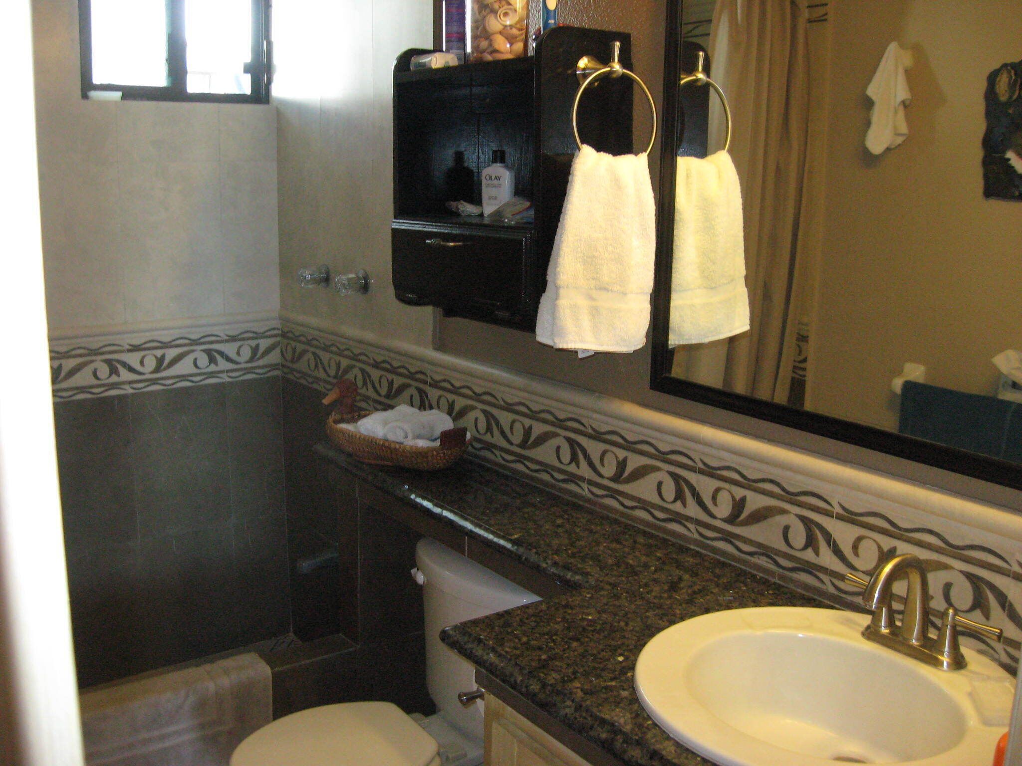 Une salle de bain équipée d’un lavabo, d’un miroir, d’un porte-serviettes et d’une petite étagère où sont rangés les articles de toilette.