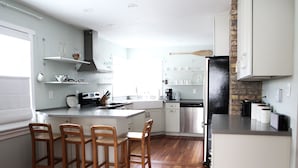Een moderne keuken met houten barkrukken, witte kastjes en een zwarte koelkast.