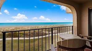 Un balcon avec vue sur une plage et l’océan.