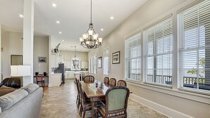 A spacious dining area with a wooden table and chairs, a chandelier, and large windows with blinds. - LAKE House with Private Heated Pool, Great for Family Gatherings. Best View! (Slidell)