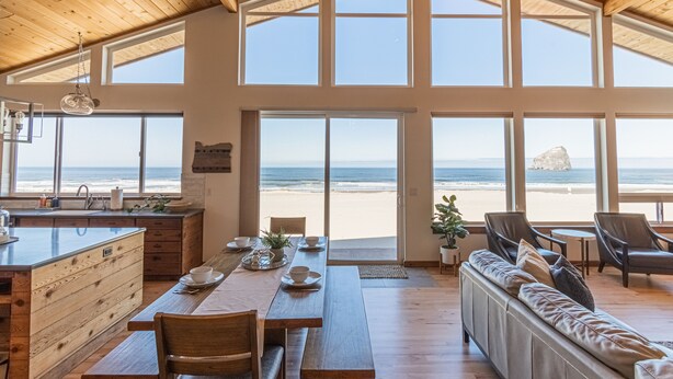 A spacious room with a large wooden ceiling, a dining area with a view of the beach, and a cozy seating area. - Ocean Views for days.....Oceanfront property that will leave you breathless! (Cloverdale)