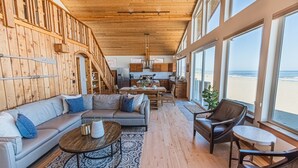 A spacious living area with a wooden ceiling, a large sofa, a coffee table, and a view of the beach through large windows. - Ocean Views for days.....Oceanfront property that will leave you breathless! (Cloverdale)
