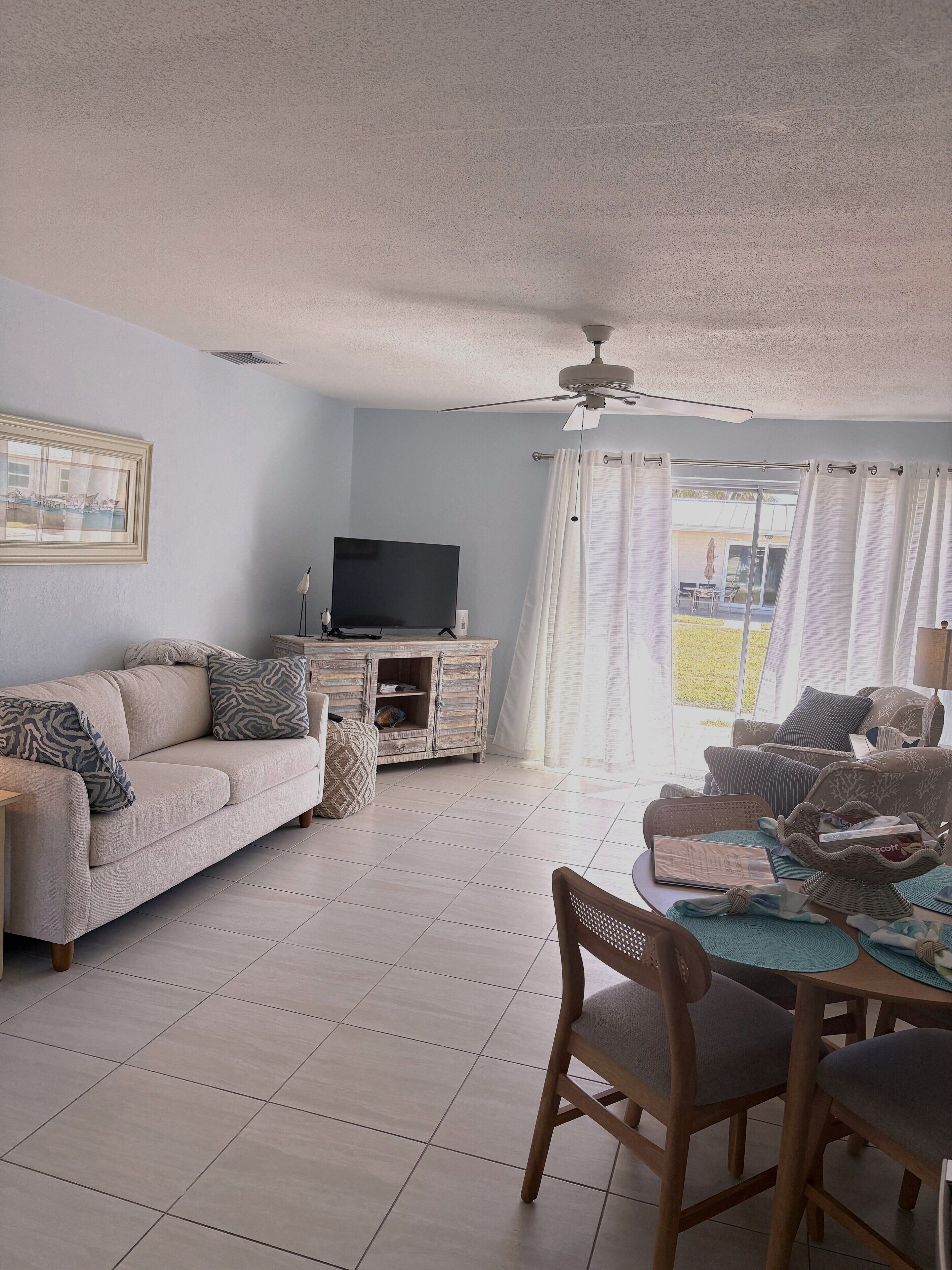 A living room with a sofa, TV, and dining area with chairs and a table.