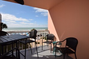 En balkon med udsigt over stranden, et bord og stole.