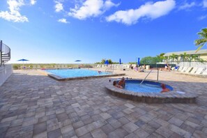 Un espace piscine comprenant deux piscines, des chaises longues et des parasols.