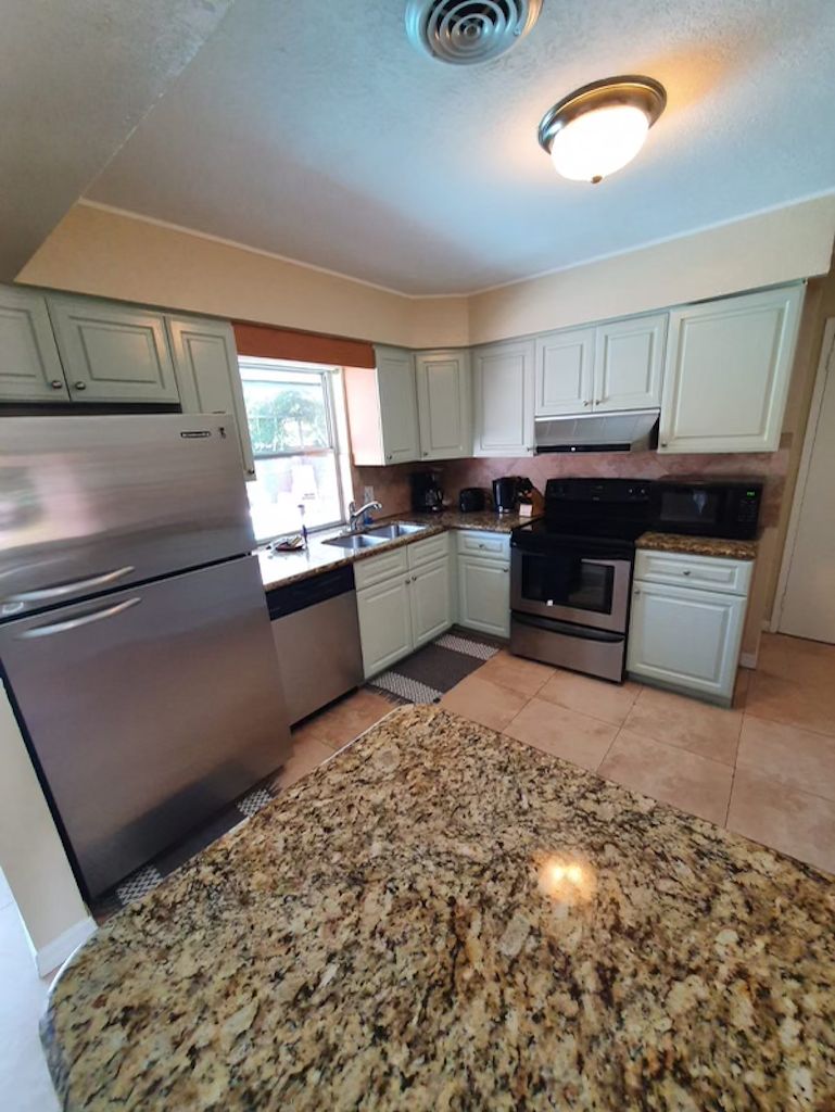 A kitchen with white cabinets, stainless steel appliances, and a granite countertop.