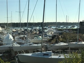 A marina with numerous boats docked, surrounded by a forested area. - HARBOR VIEW CARRIAGE HOUSE (Marion)