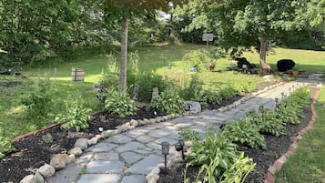 Stroll through the beautifully maintained garden, lined with a stone pathway and surrounded by lush greenery and vibrant plants.