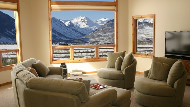 A living room with a large window offering a mountain view, two sofas, a coffee table, and a flat-screen TV. - POSTCARD VIEWS-3 min TO TOWN, 5 TO SLOPES 10 ACRES 2100 SQFT  (Crested Butte)
