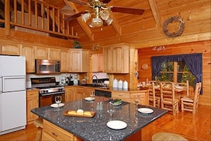Enjoy cooking in this well-appointed kitchen with a central island, modern appliances, and a dining area with a wooden table.