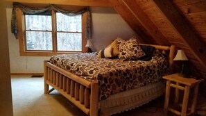Une chambre confortable avec un lit en bois, une table de chevet, une lampe et une fenêtre avec des rideaux.