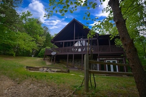 Surrounded by lush greenery, this cabin-style building features a spacious porch and a large deck.