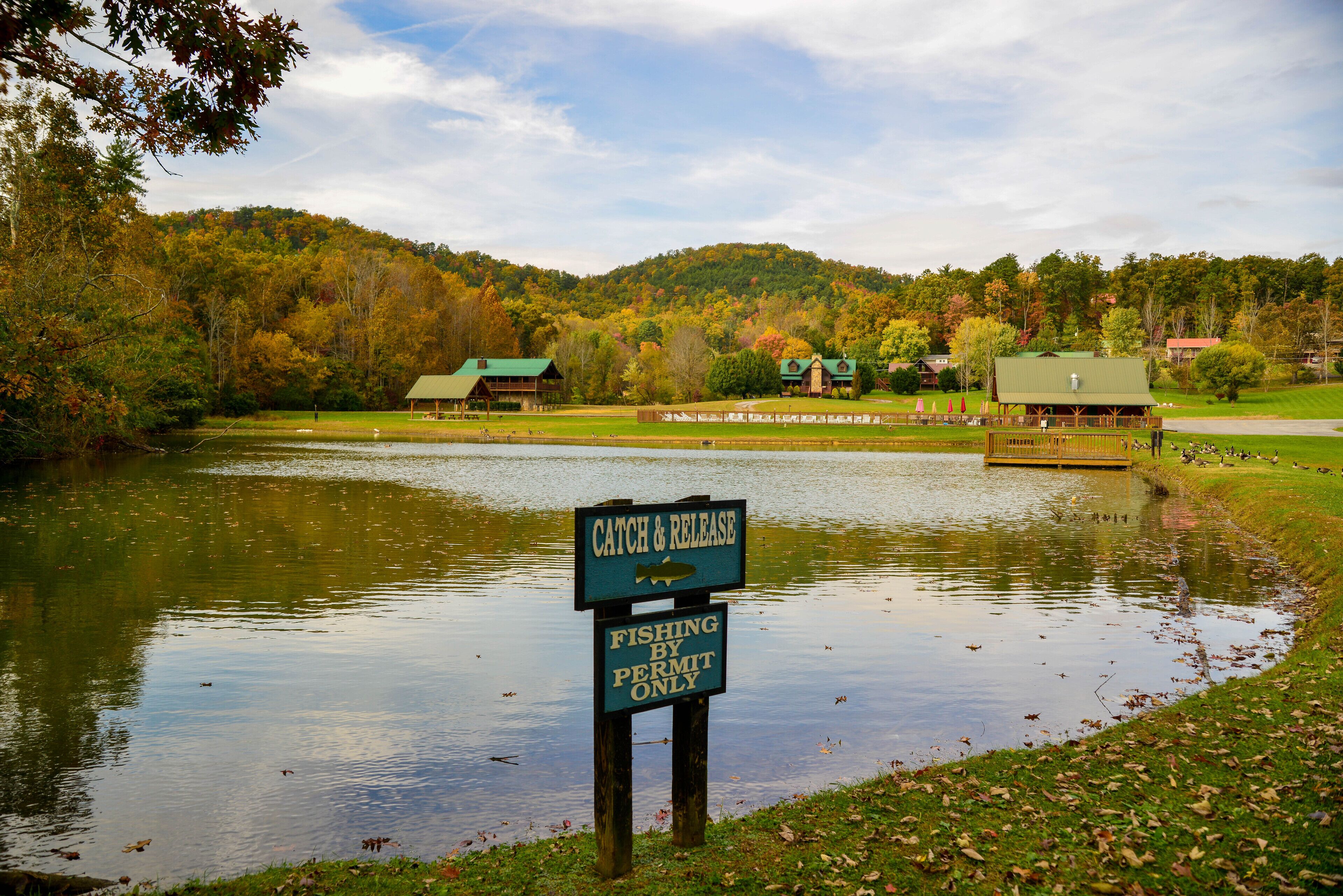 A lake with a sign indicating fishing by permit only.