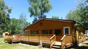 A wooden cabin with a deck and a small porch.