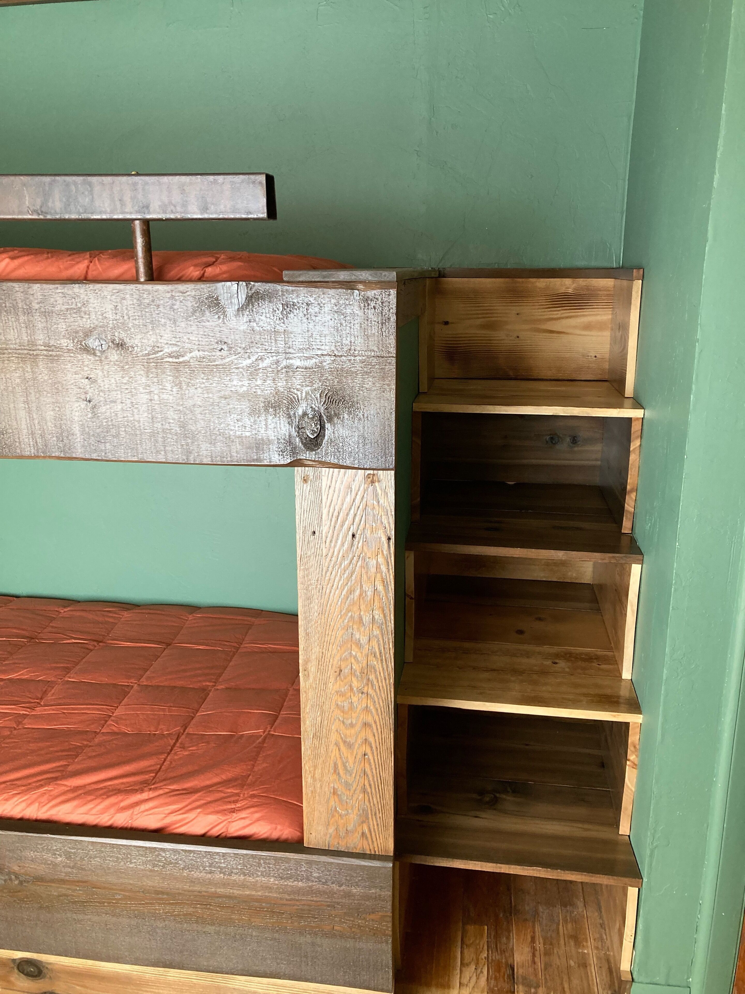 Eine hölzerne Bank mit Metallgestell, einem roten Kissen und einer grünen Wand.