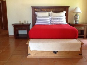 A bed with a red blanket and a wooden headboard, flanked by two nightstands with lamps. - Casa de Las Palmas . . . like your own beachfront estate on the Sea of Cortez! (Los Barriles)