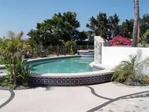 A swimming pool with a tiled edge, surrounded by palm trees and a stone wall. - Casa de Las Palmas . . . like your own beachfront estate on the Sea of Cortez! (Los Barriles)