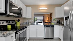 A modern kitchen with white cabinets, stainless steel appliances, granite countertops, and a view to the outside. - Water front, Bring Your Boat or drop a fishing line, enjoy a beautiful sunset ! (Punta Gorda)