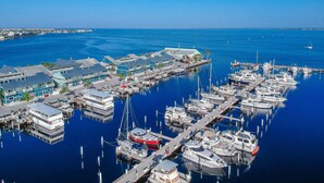 A marina with multiple boats docked, a waterfront building, and a clear blue sky. - Water front, Bring Your Boat or drop a fishing line, enjoy a beautiful sunset ! (Punta Gorda)