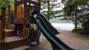 A playground with a slide and climbing structures near a lake. - Enjoy a Relaxing Weekend in the Woods at Shady Maple Cottage🌲🍂🍁 (Hoodsport)