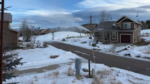Una calle residencial con casas, cielo despejado y un paisaje cubierto de nieve.