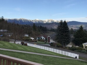 Un quartier résidentiel avec des maisons, une clôture blanche en bois et, au loin, des montagnes enneigées.